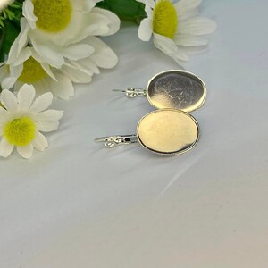 May include: A pair of silver earring blanks with round, flat, silver-toned metal settings. The settings are blank and ready to be filled with resin, paint, or other embellishments.