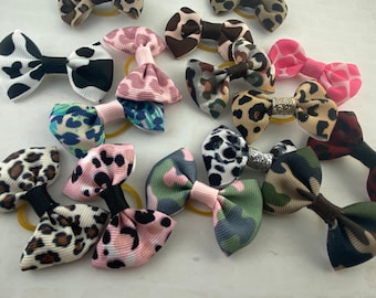 Puede incluir: Una colección de 12 lazos para el cabello coloridos con varios patrones de estampado animal, incluyendo leopardo, cebra y camuflaje. Los lazos están unidos a cintas elásticas para el cabello.