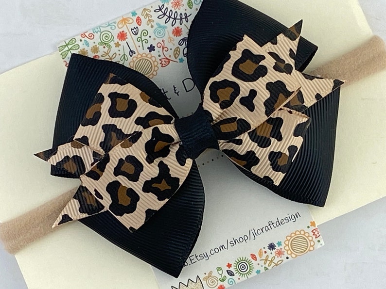 Peut inclure: Un n&oelig;ud noir et beige &agrave; imprim&eacute; l&eacute;opard sur un bandeau beige. Le n&oelig;ud est fait de ruban superpos&eacute; avec une base noire et une couche sup&eacute;rieure &agrave; imprim&eacute; l&eacute;opard. Le bandeau est de couleur neutre.