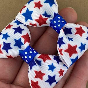 May include: Two red, white, and blue star patterned hair bows with blue and white polka dot centers.