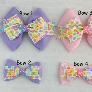 Pu&ograve; includere: Quattro fiocchi per capelli a tema pasquale di diverse dimensioni. I fiocchi sono realizzati in nastro viola e rosa con un motivo di uova di Pasqua e coniglietti bianchi e gialli. I fiocchi sono etichettati "Bow 1", "Bow 2", "Bow 3" e "Bow 4".