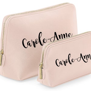 May include: Two pink zippered makeup bags with the name "Carole-Anne" printed in black cursive on each bag.