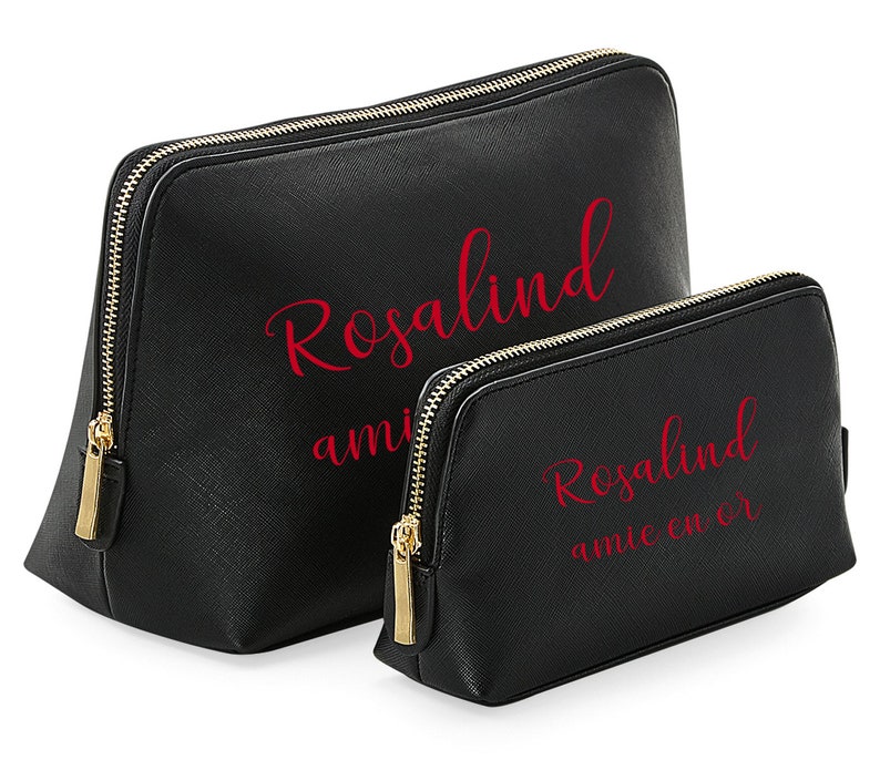 May include: Two black zippered makeup bags with gold zippers. The larger bag has the name "Rosalind" written in red cursive lettering. The smaller bag has the name "Rosalind" written in red cursive lettering and the words "amie coeur" written in red cursive lettering below.
