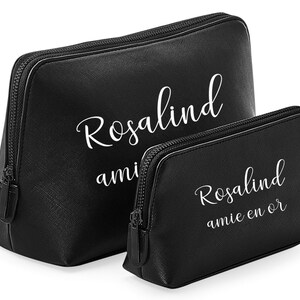 May include: Two black cosmetic bags with white text. The larger bag has the name "Rosalind" and the smaller bag has the name "Rosalind" and the phrase "amie en or". Both bags have a zipper closure.