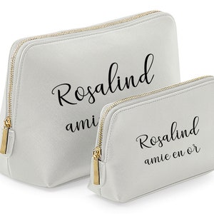 May include: Two gray zippered cosmetic bags with gold zippers. The larger bag has the name "Rosalind" printed on it. The smaller bag has the name "Rosalind" and the text "amie en or" printed on it.