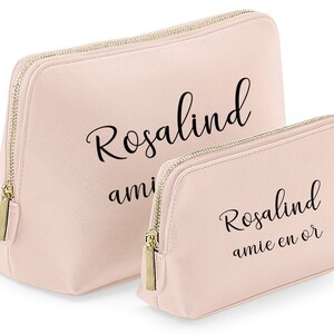 May include: Two pink zippered cosmetic bags with gold zippers. The larger bag has the text "Rosalind amie" printed on it. The smaller bag has the text "Rosalind amie en or" printed on it.
