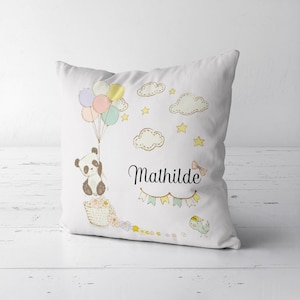 Może przedstawiać: Biała poduszka z pandą trzymającą balony, chmury, gwiazdy i imię Mathilde. Panda siedzi w koszyku z kwiatami.