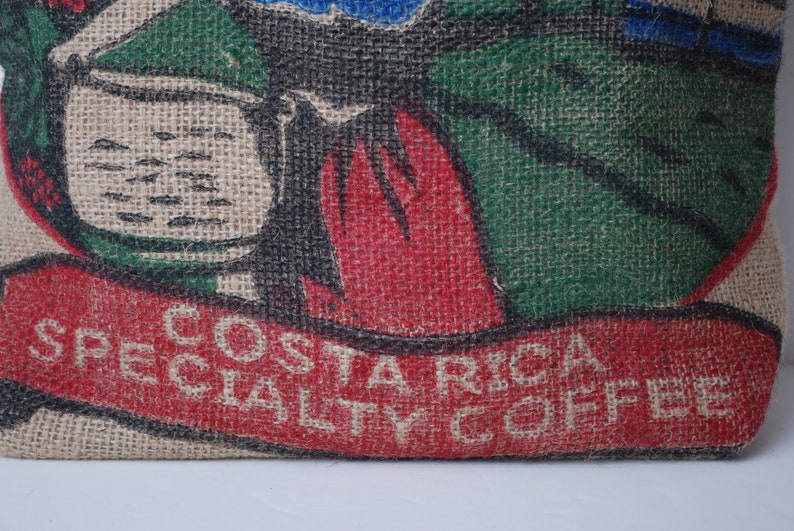 May include: A burlap sack with a red, green, and black design. The sack has the text "COSTA RICA SPECIALTY COFFEE" printed on it.