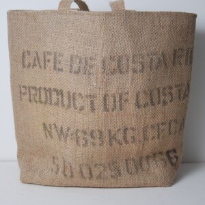 May include: A brown burlap tote bag with the text "CAFE DE COSTA" "PRODUCT OF COSTA" "NW 69 KG NET" and "SOUS VIDE" printed on the front.
