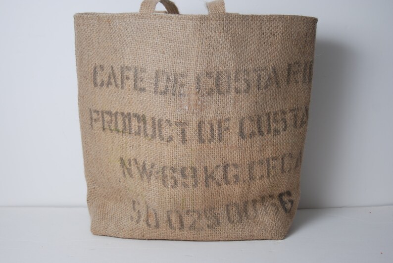 May include: A brown burlap tote bag with the text "CAFE DE COSTA" "PRODUCT OF COSTA" "NW 69 KG NET" and "SOUS VIDE" printed on the front.