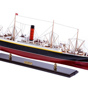 May include: A detailed wooden model of the RMS Carpathia, a British ocean liner, on a wooden base. The model is painted black and red with yellow accents. The ship has multiple masts and a red smokestack.