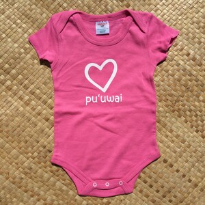 May include: Pink baby onesie with a white heart and the text "pu'uwai" on the front.