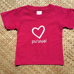 May include: A red short-sleeved t-shirt with a white heart and the text "pu'uwai" printed on the front.