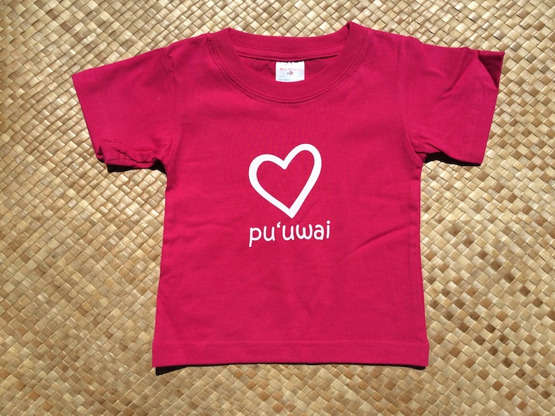 May include: A red short-sleeved t-shirt with a white heart and the text "pu'uwai" printed on the front.