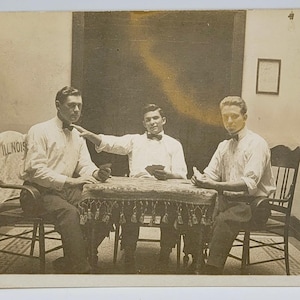 Chicos guapos jugando a las cartas ~ Foto de RPPC ~ Tres hombres con cartas en las manos ~ Camiseta de Illinois