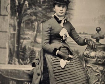 Mujer con sombrero, guantes y pañuelo en la mano. Fotografía antigua (tintype). Fondo de árboles. Moda victoriana.