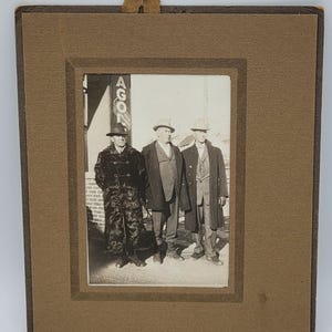 Trois hommes, chapeaux et manteaux ~ Vieux cadre en carton pour photo ~ Plaque signalétique ~ Huiles et graisses
