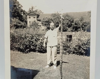 Uomo che tiene un serpente, foto vintage del 1942, ombra di serpente, ambientazione rurale.