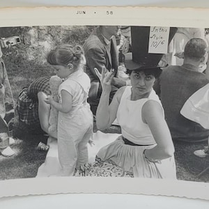 Vrouw met een soort hoge hoed ~ Vintage foto ~ Camera in de hand, linksachter ~ 1958