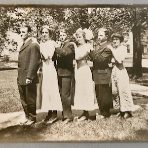 Può includere: Fotografia vintage in bianco e nero di sei persone in posa all'aperto. Tre uomini e tre donne sono in posa con le braccia incrociate. Le persone sono vestite con abiti formali, con gli uomini in abito e le donne in abito.