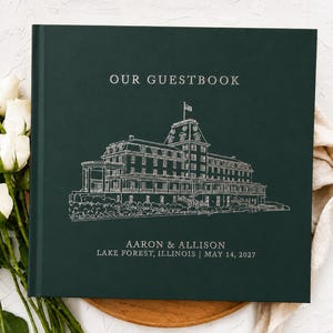 May include: A dark green guestbook featuring a white line drawing of a large building with a flag on top. The text reads OUR GUESTBOOK, AARON & ALLISON, LAKE FOREST, ILLINOIS | MAY 14, 2027. The cover has a matte finish and silver-toned lettering.