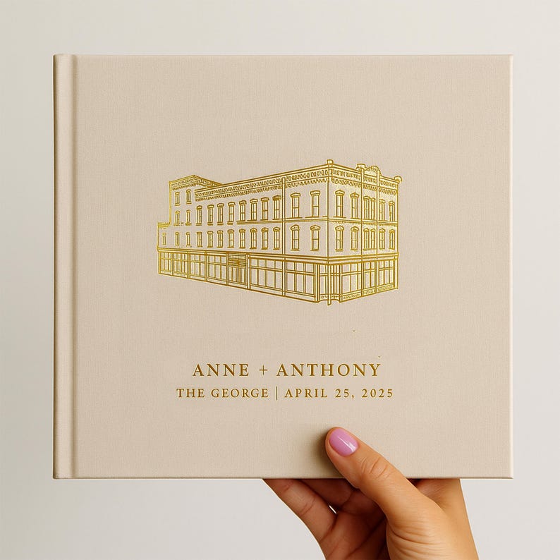 May include: A beige square book with a gold illustration of a building on the cover. The text "ANNE + ANTHONY" and "THE GEORGE | APRIL 25, 2025" are printed in gold below the building illustration.
