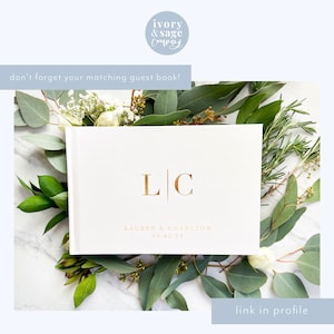 May include: A white guest book with gold lettering, featuring the initials "LC" and the names "LAUREN & CHARLTON" with the date "09.05.22". The book is surrounded by greenery and white flowers. The text "don't forget your matching guest book!" is visible.