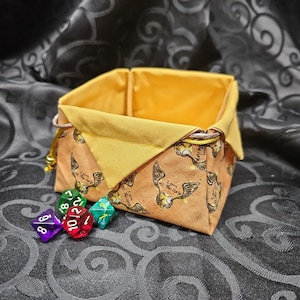 May include: A yellow fabric dice bag with a brown and gold print of wings and the text "I solemnly swear that I am up to no good". The bag is filled with colorful dice.