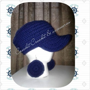 May include: A blue crocheted baseball cap with a matching pair of crocheted earrings. The cap has a curved brim and the earrings are round.