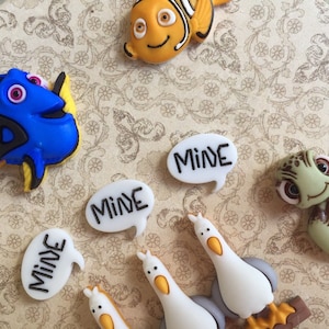 May include: A collection of colorful resin character embellishments featuring characters from the movie "Finding Nemo". Includes Dory, Nemo, a sea turtle, and seagulls. Several speech bubbles say "MINE".