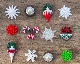 May include: A collection of Christmas-themed embellishments, including white snowflakes, red and green ornaments, candy canes, and floral designs. The embellishments are in various shapes and sizes, perfect for holiday crafts.