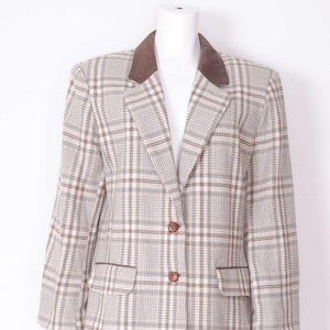 May include: A plaid blazer with a brown velvet collar. The blazer has a single-breasted closure with two buttons and a pocket on the left side.