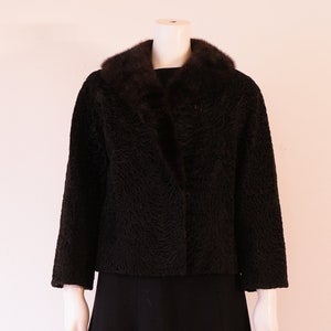 Peut inclure: Une veste en fourrure noire avec un grand col en fourrure. La veste est courte et a une forme légèrement évasée. La veste est sur un mannequin.