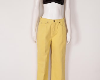 Può includere: Un reggiseno a triangolo in velluto nero e pantaloni gialli sono esposti su un manichino. I pantaloni sono di colore giallo chiaro uniforme con un classico design a cinque tasche. Il reggiseno ha spalline sottili.