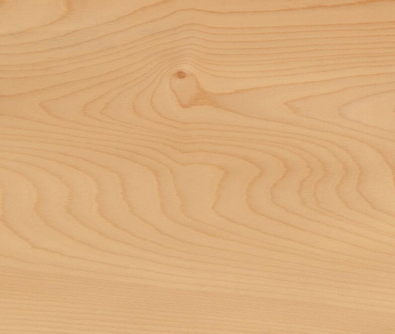 May include: Close-up of a light-colored wood grain pattern. The wood has a natural, warm tone with visible grain lines and a knot. The surface appears smooth and polished, showcasing the wood's natural beauty.