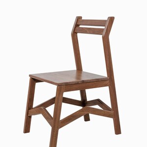 May include: A wooden chair with a simple, modern design. The chair is constructed from a warm-toned wood and features a rectangular seat, a slatted backrest, and angled legs. The chair is suitable for dining or as an accent piece.