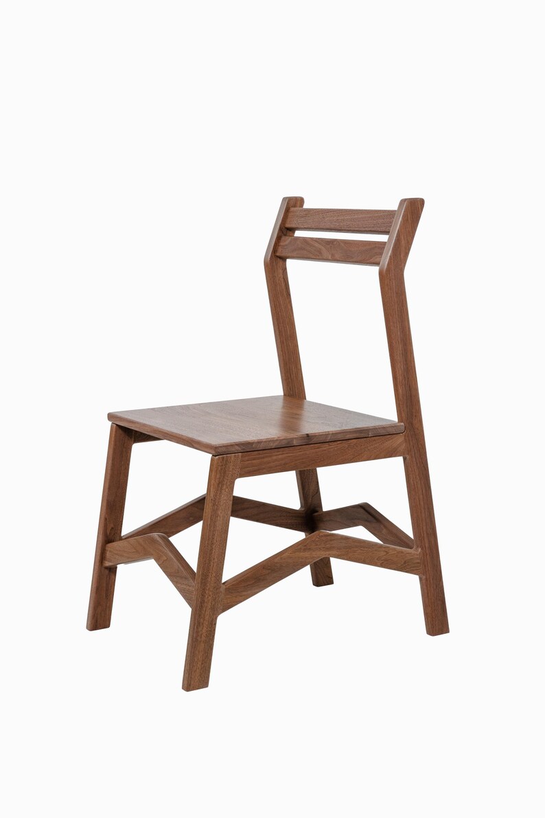May include: A wooden chair with a simple, modern design. The chair is constructed from a warm-toned wood and features a rectangular seat, a slatted backrest, and angled legs. The chair is suitable for dining or as an accent piece.