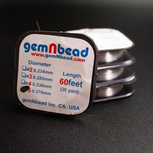 May include: A stack of clear, thin beading wire spools with white labels featuring the text gemNbead, www.gemNbead.com, and a diameter chart listing sizes #2 0.234mm, #3 0.285mm, #4 0.330mm, and #5 0.370mm, with a total length of 60 feet or 20 yards.