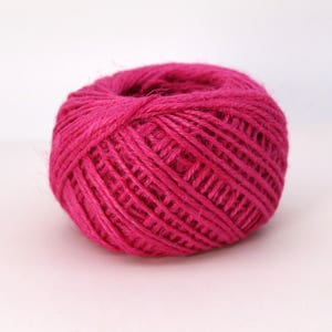 May include: A ball of vibrant fuchsia-colored twine. The twine is tightly wound, forming a spherical shape. The texture appears slightly rough, suggesting a natural fiber. Ideal for crafting, gift wrapping, or other creative projects.