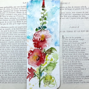 May include: A rectangular paper bookmark featuring a watercolor painting of two vibrant red hollyhock flowers on a green stem against a light blue sky background. A thin red ribbon is attached to the top center of the bookmark.