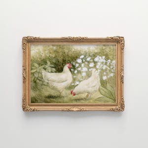 May include: A framed painting featuring two white chickens with red combs in a garden setting. The artwork is set in a gold ornate frame. The background includes green foliage and white flowers, creating a pastoral scene.