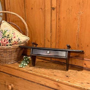 May include: A white ceramic mug with a black handle and the text "But First, Coffee" in a bold, black font. The mug is set against a blurred background, suggesting a cozy setting.