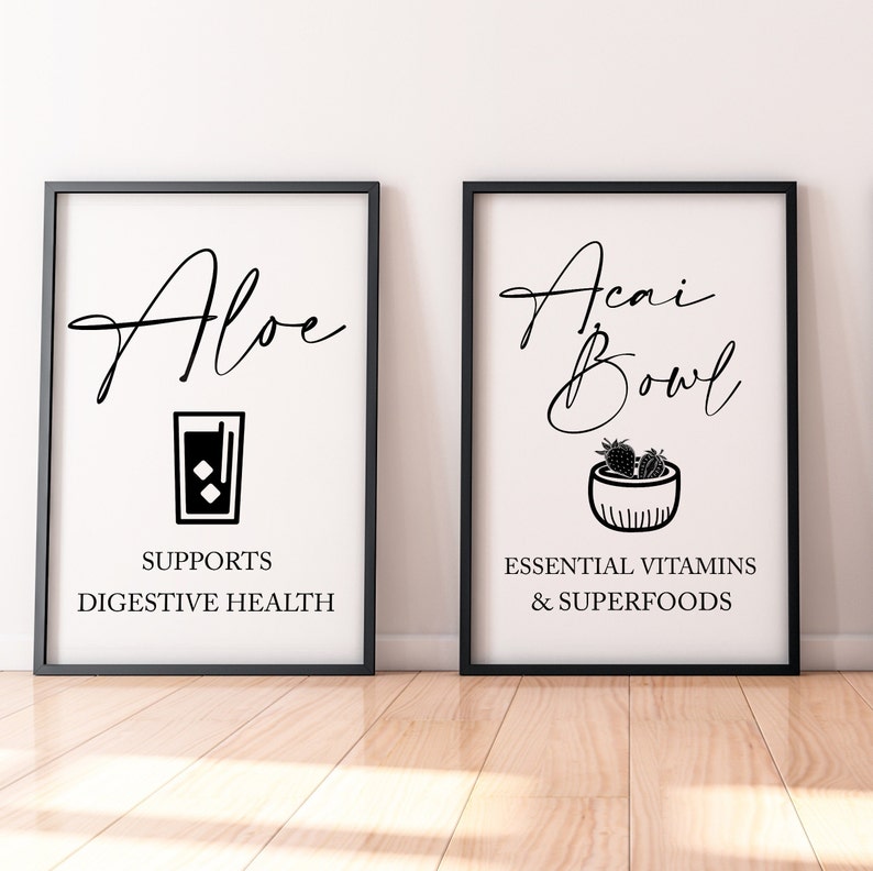 May include: Two black framed prints with white backgrounds. The left print features a black illustration of a glass of aloe juice and the text "Aloe" and "Supports Digestive Health". The right print features a black illustration of a bowl of acai with the text "Acai Bowl" and "Essential Vitamins & Superfoods".