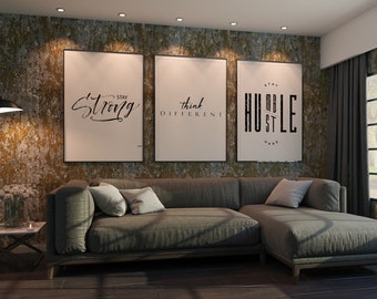 Puede incluir: Tres carteles motivacionales enmarcados con citas inspiradoras en una pared de una sala de estar. Los carteles son en blanco y negro y tienen un diseño moderno. Las citas son "Mantente fuerte", "Piensa diferente" y "Humildad y trabajo duro".