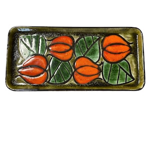 Può includere: Un vassoio rettangolare in ceramica con sfondo verde e marrone. Il vassoio è decorato con un motivo ripetitivo di fiori stilizzati arancioni e foglie verdi.