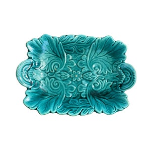 Può includere: Un piatto da portata in ceramica blu turchese con un design di foglie e fiori decorativi.