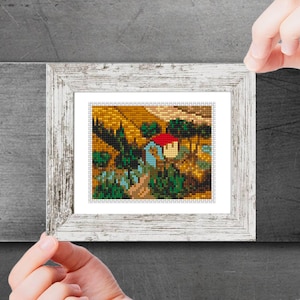 May include: A framed painting depicting a rural scene with a small cottage, trees, and a field. The cottage has a red roof and the field is a golden yellow colour.