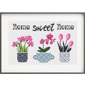Könnte beinhalten: Kreuzstich-Kunstwerk mit dem Schriftzug "Home sweet Home" über drei Topfblumen. Die Blumen sind rosa Gerbera, eine Orchidee und rosa Tulpen. Die Töpfe haben geometrische Muster in Blau, Grau und Schwarz.