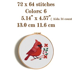 May include: A cross-stitch embroidery hoop featuring a red cardinal bird perched on a branch with red flowers and green leaves. The design is 5.14" x 4.57" and uses 6 colors. The text reads "72 x 64 stitches" and "Colors: 6".