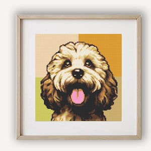 Puede incluir: Un primer plano de un perro marrón y blanco con la lengua rosa que sobresale. El perro mira directamente a la cámara y tiene una expresión feliz. El fondo es de color amarillo y naranja.